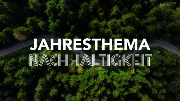 Eine Straße im Wald mit der Aufschrift Jahresthema Nachhaltigkeit